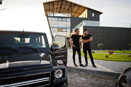 Two asian brothers man wear on all black posed near suv cars.