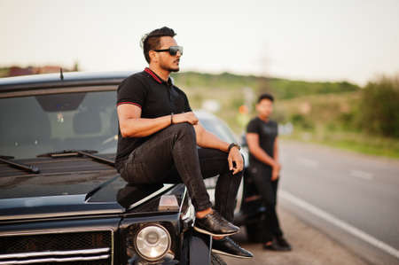 Two asian brothers man wear on all black posed near suv cars.