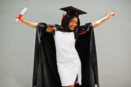 Young female african american student with diploma poses outdoors.の写真素材