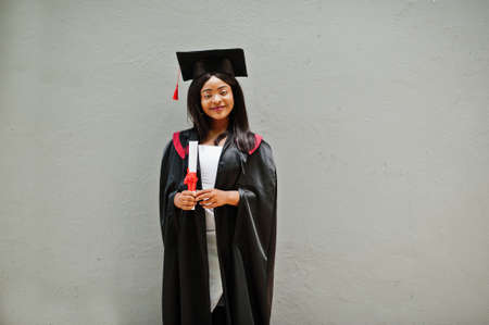 Young female african american student with diploma poses outdoors.の写真素材