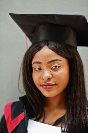 Young female african american student with diploma poses outdoors.