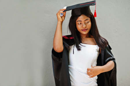 Young female african american student with diploma poses outdoors.の写真素材