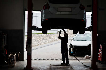Car repair and maintenance theme. Mechanic in uniform working in auto service.の写真素材