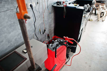 Car repair and maintenance theme. Car battery, electric vehicle battery charger via jumper cable.