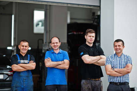 Car repair and maintenance theme. Three mechanic and manager in uniform in auto service.の写真素材