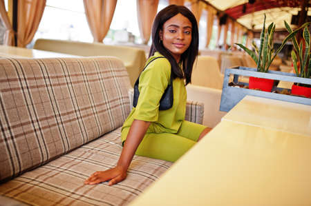 Black women wear in green summer clothes sit in tent cafe. African american girl.