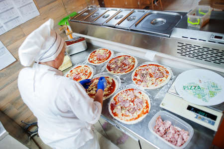Female chef preparing pizza in restaurant kitchen.の写真素材