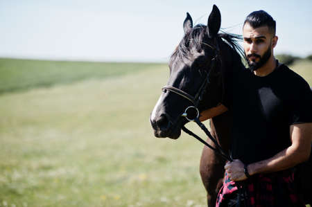Arab tall beard man wear in black with arabian horse.の写真素材