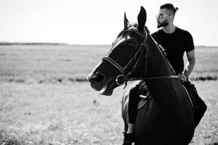 Arab tall beard man wear in black and sunglasses ride arabian horse.の写真素材