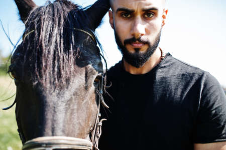 Arab tall beard man wear in black with arabian horse.の写真素材