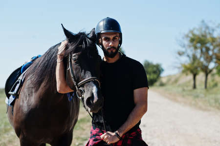 Arab tall beard man wear in black helmet with arabian horse.