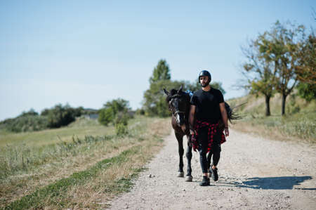 Arab tall beard man wear in black helmet with arabian horse.の写真素材