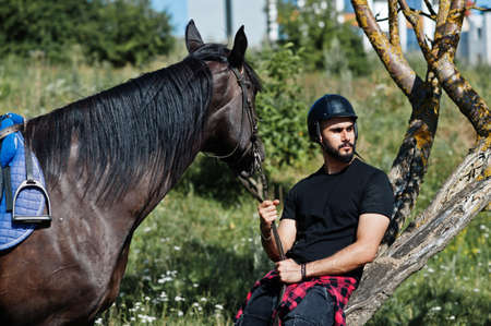 Arab tall beard man wear in black helmet with arabian horse.の写真素材