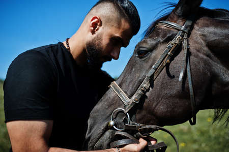 Arab tall beard man wear in black with arabian horse.の写真素材