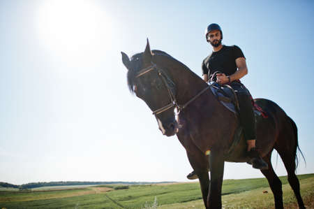 Arab tall beard man wear in black helmet, ride arabian horse.の写真素材