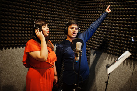 Young asian duet singers with microphone recording song in record music studio.の写真素材