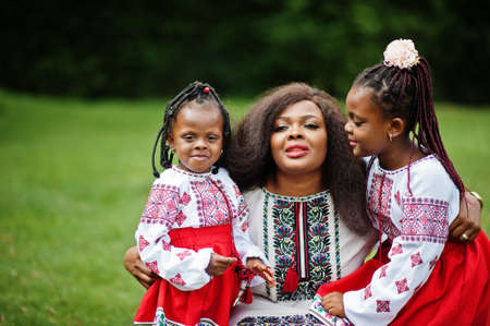 African mother with daugters in traditional clothes at park.