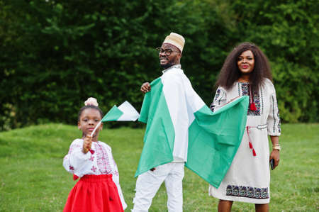 African family in traditional clothes with nigerian flags at park.の写真素材