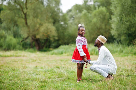 African father with daughter in traditional clothes at park.の写真素材