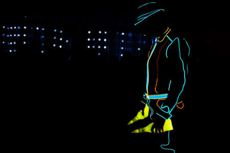 Professional barman and led light show. Silhouette of modern bartender shaking drink at night...