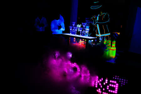 Professional barman and led light show. Silhouette of modern bartender shaking drink at night cocktail bar.の写真素材