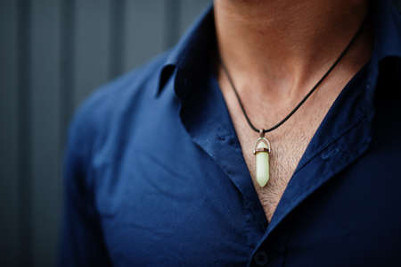 Close up hexagon point quartz pendant at man.
