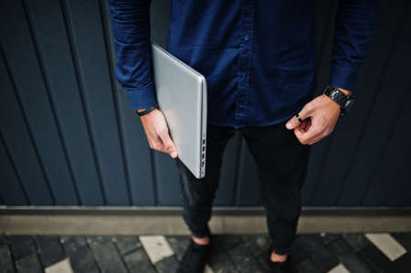 Close up photo of man hands with laptop against steel wall.の写真素材