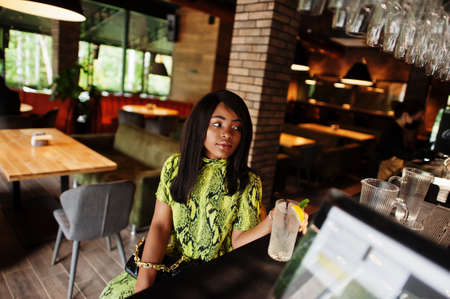 Glamor african american woman wear fashionable snake dress and sunglasses pose on bar.の写真素材