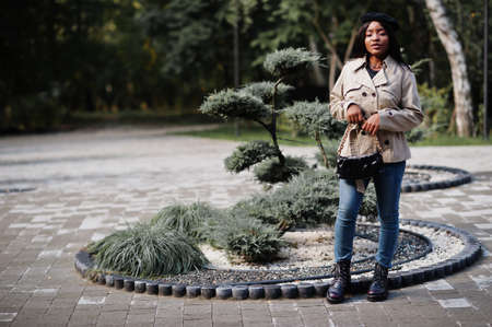 Fashionable african american woman wear beret and coat with handbag posing outdoor.の写真素材