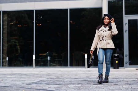 Fashionable african american woman wear beret and coat with handbag posing outdoor.の写真素材