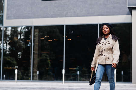 Fashionable african american woman wear beret and coat with handbag posing outdoor.の写真素材