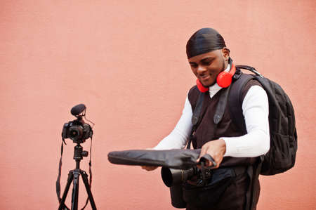 Young professional african american videographer holding professional camera with pro equipment....