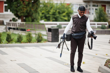 Young professional african american videographer holding professional camera with pro equipment....