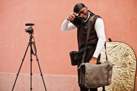 Young professional african american videographer holding professional camera with pro equipment....