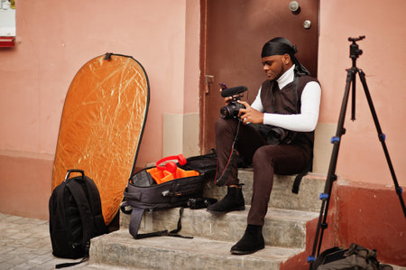 Young professional african american videographer holding professional camera with pro equipment....