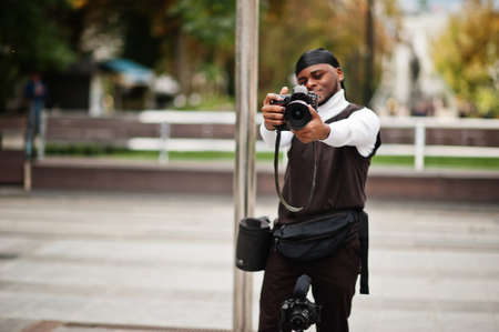 Young professional african american videographer holding professional camera with pro equipment. Afro cameraman wearing black duraq making a videos.の写真素材