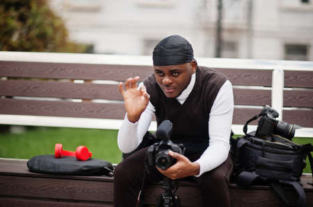 Young professional african american videographer holding professional camera with pro equipment. Afro cameraman wearing black duraq making a videos.の写真素材