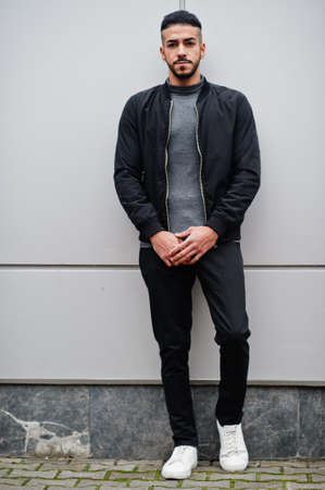 Portrait of stylish arab beard man wear gray turtleneck and black jaket. Arabian model guy against steel wall.の写真素材