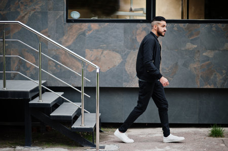 Portrait of stylish arab beard man wear gray turtleneck and black jaket. Arabian model guy walking down stairs.の写真素材