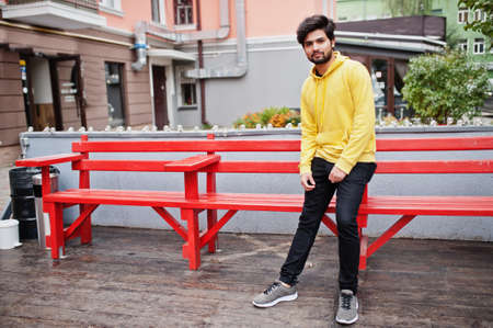 Urban young hipster indian man in a fashionable yellow sweatshirt. Cool south asian guy wear hoodie.の写真素材