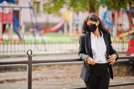 Gorgeous indian woman wear formal and black face mask, posing at street during covid pandemia.の写真素材