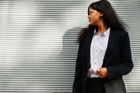 Gorgeous indian woman wear formal posing against gray wall.
