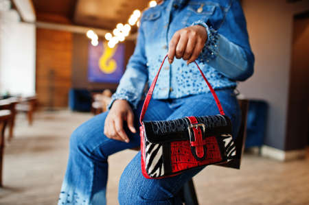 Lovely african american woman with in blue stylish jeans show handbag.