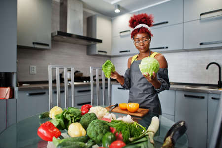 African american woman preparing healthy food at home kitchen. She hold a cabbage.の写真素材