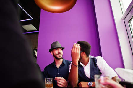 Group of handsome retro well-dressed man gangsters spend time at club, sitting and drinking whiskey....