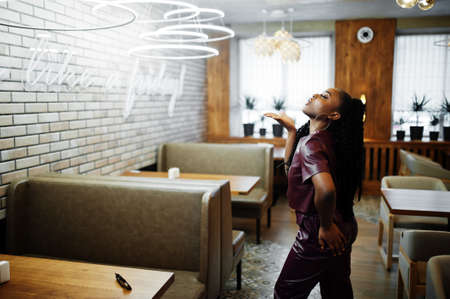 Beautiful african american woman in red leather costume pose at restaurant.