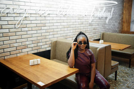 Beautiful african american woman in red leather costume pose at restaurant.の写真素材