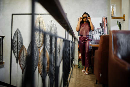 Beautiful african american woman in red leather costume pose at restaurant.