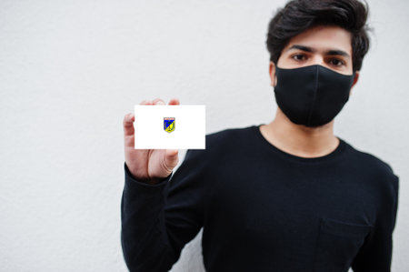 Indonesian man wear all black with face mask hold Central Sulawesi flag in hand isolated on white background. Provinces of Indonesia coronavirus concept.の写真素材