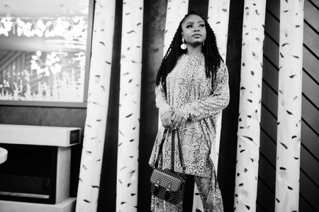 Young stylish african american woman, with black handbag pose indoor.の写真素材